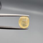 ​A 2-carat natural Ceylon yellow sapphire featuring a cushion faceted cut and high transparency, presented in a white jeweler's box.