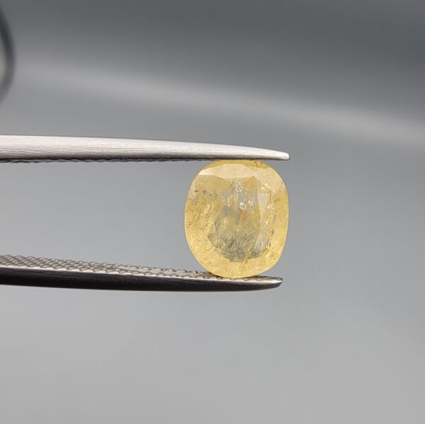 ​A 2-carat natural Ceylon yellow sapphire featuring a cushion faceted cut and high transparency, presented in a white jeweler's box.