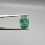 A 2.64-carat natural Zambian emerald with a vivid green color and oval faceted cut, displaying characteristic internal inclusions and high transparency in a jeweler's display.