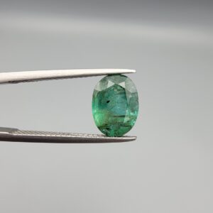 A 2.64-carat natural Zambian emerald with a vivid green color and oval faceted cut, displaying characteristic internal inclusions and high transparency in a jeweler's display.