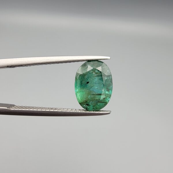 A 2.64-carat natural Zambian emerald with a vivid green color and oval faceted cut, displaying characteristic internal inclusions and high transparency in a jeweler's display.
