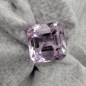 ​A massive 24-carat natural Brazilian amethyst with a light purple lavender color and faceted cut, professionally displayed in a jeweler's box.