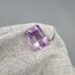 ​A large 16.73-carat natural Brazilian amethyst with a soft light purple lavender color and precision faceted cut, displayed in a white jeweler's box.