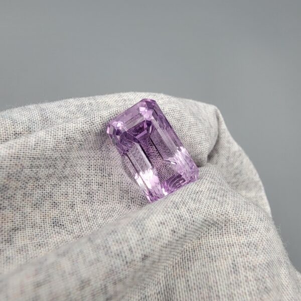 ​A large 16.73-carat natural Brazilian amethyst with a soft light purple lavender color and precision faceted cut, displayed in a white jeweler's box.