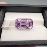 A massive 15.18-carat natural Brazilian amethyst with a soft light purple lavender color and precision faceted cut, displayed in a white jeweler's box.