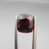​A 6.08-carat natural red garnet from Madagascar, featuring a deep reddish color and sparkling faceted cut, professionally displayed in a white jeweler's box.