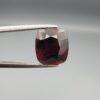 ​A 6.08-carat natural red garnet from Madagascar, featuring a deep reddish color and sparkling faceted cut, professionally displayed in a white jeweler's box.