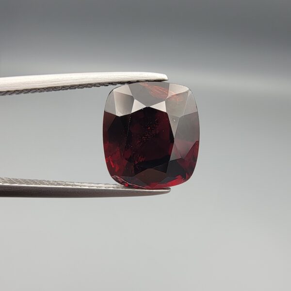 ​A 6.08-carat natural red garnet from Madagascar, featuring a deep reddish color and sparkling faceted cut, professionally displayed in a white jeweler's box.