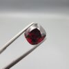 ​A 6.81-carat natural red garnet from Madagascar, featuring a deep reddish color and sparkling faceted cut, professionally displayed in a white jeweler's box.