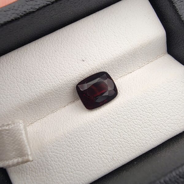 A 3.26-carat natural red garnet from Madagascar with a vibrant reddish hue and precision faceted cut, displayed in a professional jeweler's box.