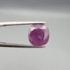 A large 6.83-carat natural Madagascar ruby with a purplish-red color, featuring visible natural mountain marks and cracks on the surface and back, displayed in a jeweler's box.