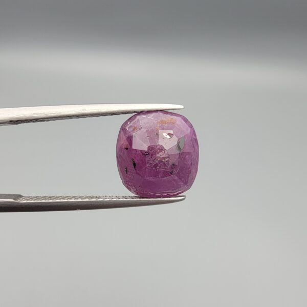 A large 6.83-carat natural Madagascar ruby with a purplish-red color, featuring visible natural mountain marks and cracks on the surface and back, displayed in a jeweler's box.