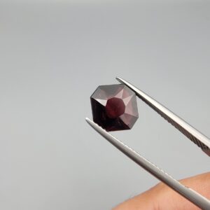A 3.10-carat natural red garnet from Madagascar with an octagon step cut and vibrant reddish sparkle, shown in a professional jeweler's box.