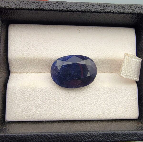 A massive 11.25-carat natural blue sapphire from Afghanistan with an oval faceted cut and deep blue color, professionally displayed in a white jeweler's box.