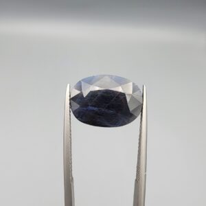 A massive 10.56-carat natural blue sapphire from Afghanistan with an oval faceted cut and deep royal blue color, professionally displayed in a white jeweler's box.
