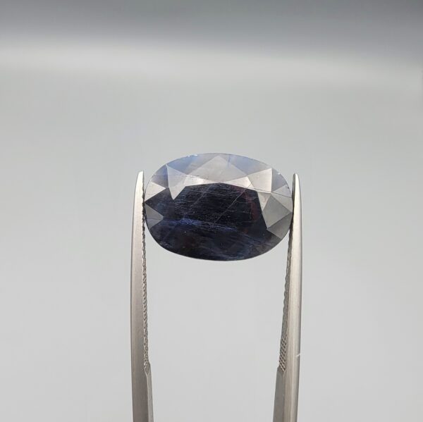 A massive 10.56-carat natural blue sapphire from Afghanistan with an oval faceted cut and deep royal blue color, professionally displayed in a white jeweler's box.