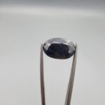 A 7.84-carat natural blue sapphire from Afghanistan with an oval faceted cut and deep royal blue color, professionally displayed in a white jeweler's box.
