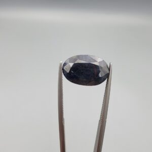 A 7.84-carat natural blue sapphire from Afghanistan with an oval faceted cut and deep royal blue color, professionally displayed in a white jeweler's box.