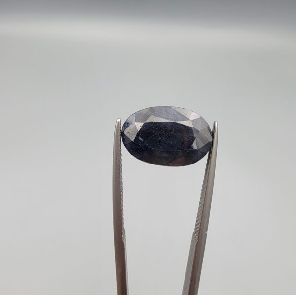 A 7.84-carat natural blue sapphire from Afghanistan with an oval faceted cut and deep royal blue color, professionally displayed in a white jeweler's box.