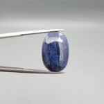 An extraordinary 25.07-carat natural blue sapphire from Afghanistan, featuring an oval faceted cut and deep blue saturation, displayed in a professional jeweler's box.