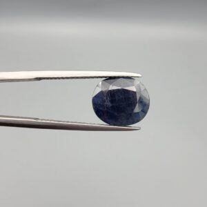 ​A 4.98-carat natural blue sapphire from Afghanistan with an oval faceted cut and deep royal blue color, presented in a professional white jeweler's box.