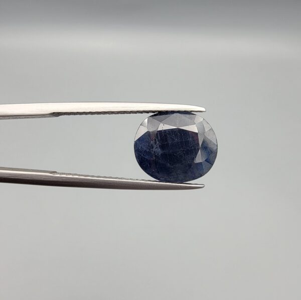 ​A 4.98-carat natural blue sapphire from Afghanistan with an oval faceted cut and deep royal blue color, presented in a professional white jeweler's box.