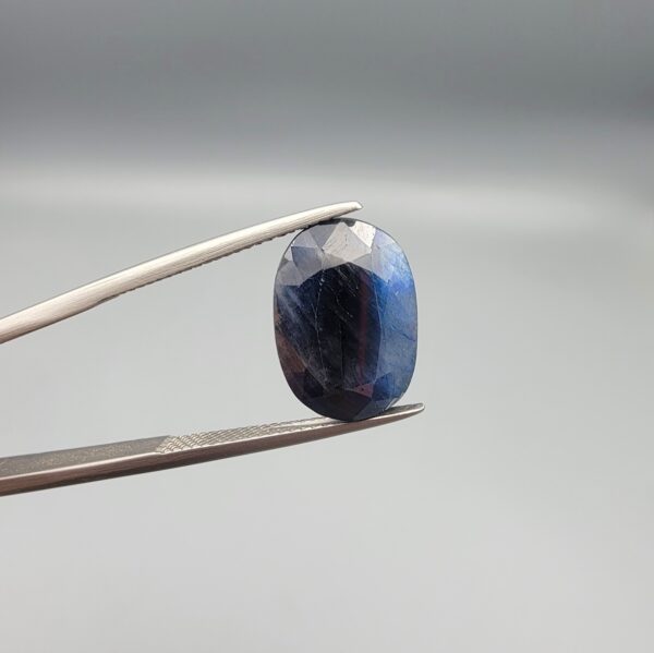 A 9.09-carat natural blue sapphire from Afghanistan with a classic oval faceted cut and rich royal blue color, professionally displayed in a white jeweler's box.