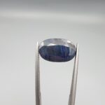 ​A 6.52-carat natural blue sapphire from Afghanistan with an oval faceted cut and deep royal blue color, professionally displayed in a white jeweler's box.
