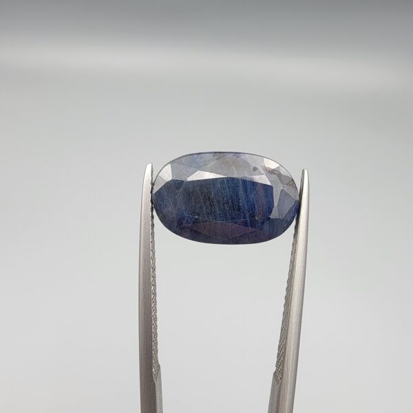 ​A 6.52-carat natural blue sapphire from Afghanistan with an oval faceted cut and deep royal blue color, professionally displayed in a white jeweler's box.