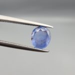 A rare 1.45-carat unheated natural blue sapphire (Neelam) from Ceylon, Sri Lanka, featuring a masterfully faceted oval cut and vivid royal blue color, presented in a professional white jeweler's box.