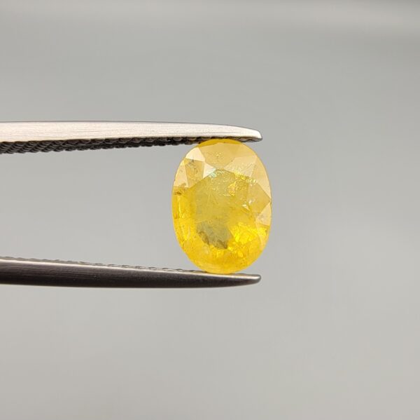 A rare 1.50-carat unheated natural yellow sapphire (Pukhraj) from Ceylon, Sri Lanka, featuring a masterfully faceted oval cut and bright lemon-yellow saturation, presented in a professional white jeweler's box.