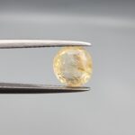A rare 2.44-carat unheated natural yellow sapphire (Pukhraj) from Ceylon, Sri Lanka, featuring a masterfully faceted oval cut and deep golden-yellow saturation, held in professional jeweler's tweezers.