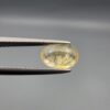 A rare 1.67-carat unheated natural yellow sapphire (Pukhraj) from Ceylon, Sri Lanka, featuring a masterfully faceted oval cut and bright lemon-yellow saturation, shown in professional jeweler's tweezers.