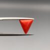 A 2.20-carat natural Italian red coral in a polished triangle cabochon shape, showcasing a smooth surface and rich orange-red tone in a jeweler's display.
