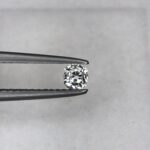 A 0.23-carat natural white diamond (Heera) with a brilliant cushion shape cut, displaying high fire and sparkle under professional lighting, held in jeweler's tweezers.