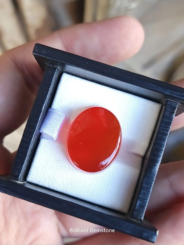 ​A large 23.32-carat Yemeni reddish carnelian agate (Aqeeq) with exceptional high clarity and a smooth cabochon polish, shown under natural lighting.