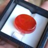 ​A large 23.32-carat Yemeni reddish carnelian agate (Aqeeq) with exceptional high clarity and a smooth cabochon polish, shown under natural lighting.