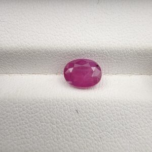A 1.41-carat natural pinkish-red ruby from Mozambique with an oval faceted cut, showcasing brilliant luster and high transparency, presented in a professional jeweler's box.