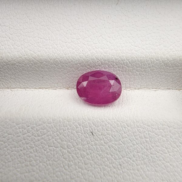 A 1.41-carat natural pinkish-red ruby from Mozambique with an oval faceted cut, showcasing brilliant luster and high transparency, presented in a professional jeweler's box.