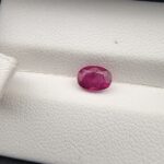 A 1.16-carat natural pinkish-red ruby from Mozambique in an oval faceted cut, displaying vivid luster and high clarity, presented in a professional jeweler's box.