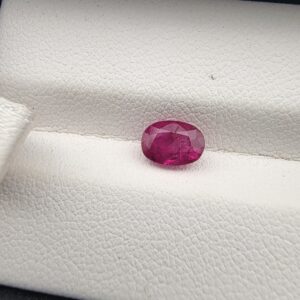 A 1.16-carat natural pinkish-red ruby from Mozambique in an oval faceted cut, displaying vivid luster and high clarity, presented in a professional jeweler's box.