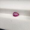 A 0.81-carat natural red ruby from Mozambique in a pear faceted cut, showing vibrant red color and an authentic natural surface pit, displayed in a professional jeweler's box.