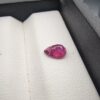A 0.81-carat natural red ruby from Mozambique in a pear faceted cut, showing vibrant red color and an authentic natural surface pit, displayed in a professional jeweler's box.