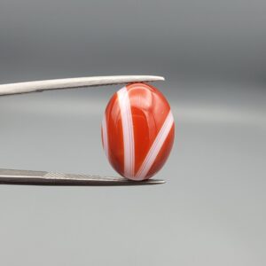 A 9.32-carat natural orangish-red Aqeeq gemstone with a prominent horizontal white band, presented in a professional jeweler's box.