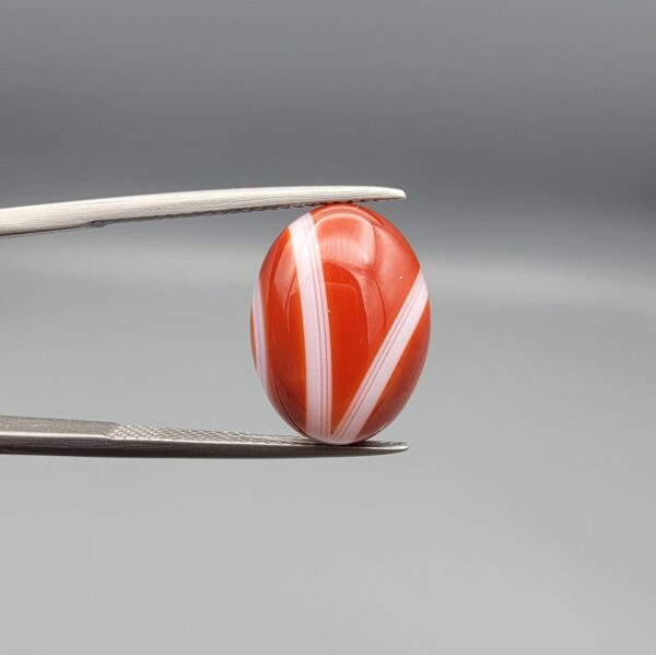 A 9.32-carat natural orangish-red Aqeeq gemstone with a prominent horizontal white band, presented in a professional jeweler's box.