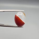 An 8.75-carat natural dual-colored Aqeeq gemstone, featuring a reddish lower half and a crystalline white upper layer, presented in a professional jeweler's box.