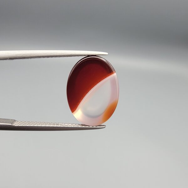 An 8.75-carat natural dual-colored Aqeeq gemstone, featuring a reddish lower half and a crystalline white upper layer, presented in a professional jeweler's box.
