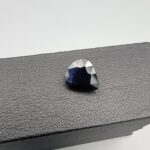 A 3.67-carat natural blue sapphire from Kanchanaburi, Thailand, featuring a deep blue color and a pear faceted cut, displayed in a white jeweler's box.