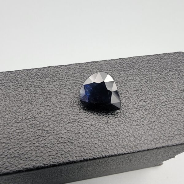 A 3.67-carat natural blue sapphire from Kanchanaburi, Thailand, featuring a deep blue color and a pear faceted cut, displayed in a white jeweler's box.