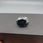 A 4.77-carat natural blue sapphire from Kanchanaburi, Thailand, featuring a classic oval faceted cut and a deep midnight blue color, displayed in a professional jeweler's box.